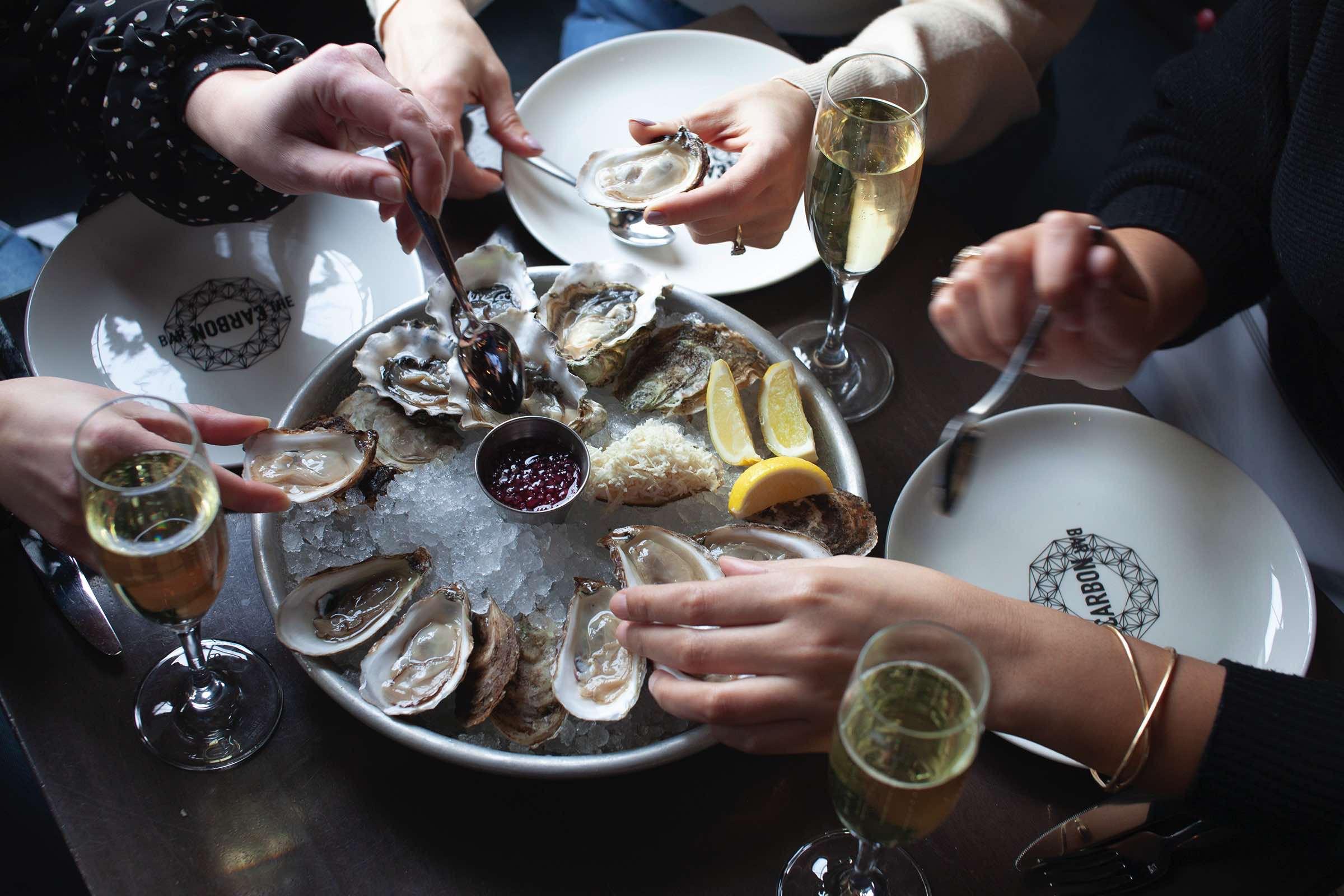 Overhead shot of oysters, lemon, and sparkling wine on the bar