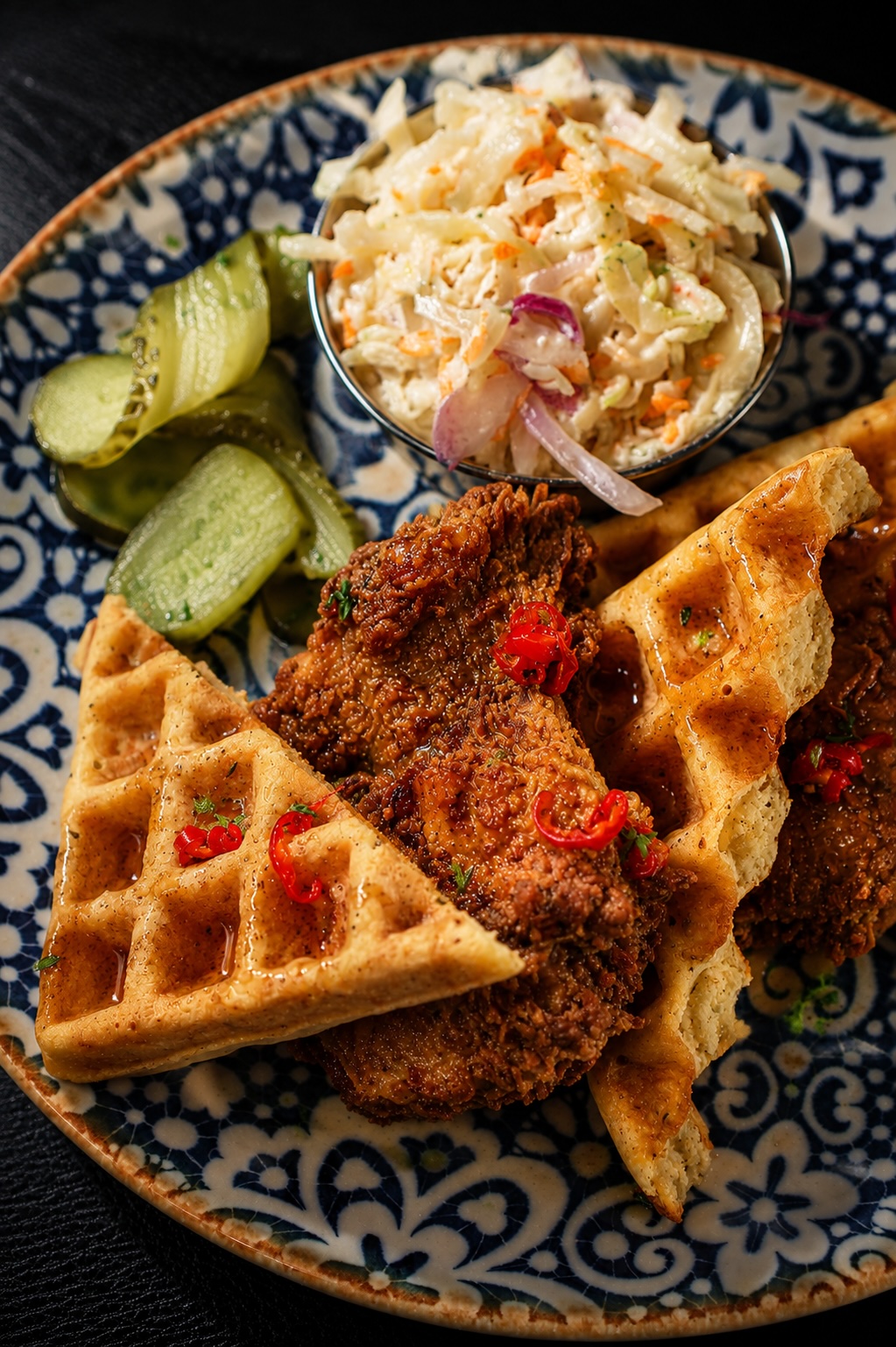 Chicken and waffles with hot honey, coleslaw and pickles on a hand-painted plate at The Carbon Bar Sunday brunch